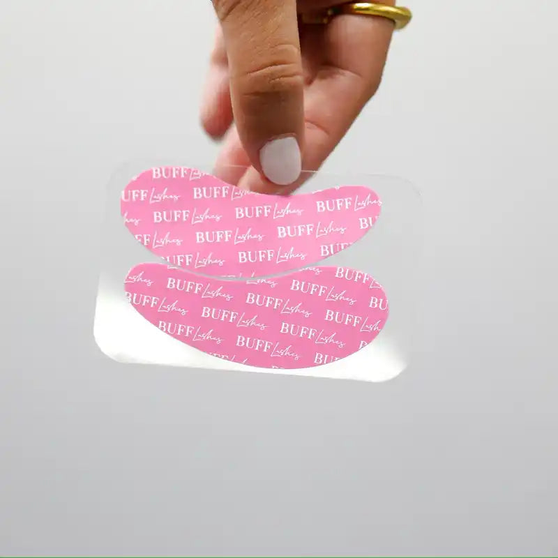 Two pink, heart-shaped under-eye patches with a ’BUFF Lashes’ pattern.
